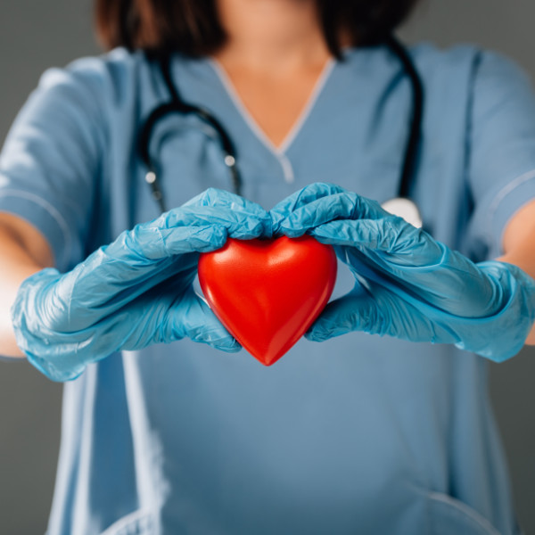 Woman in scrubs holding a plastic heart